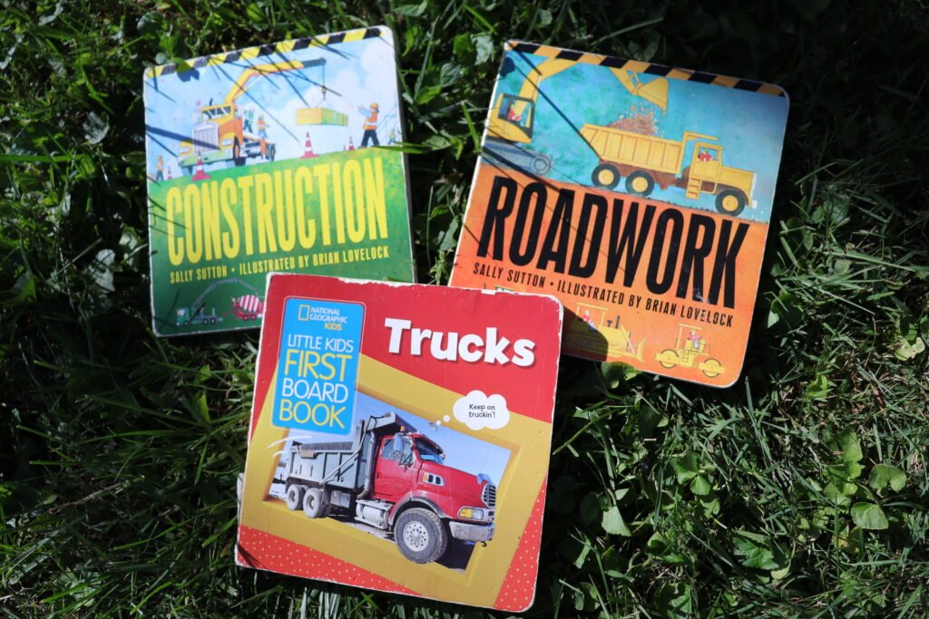 three toddler books about trucks on the grass